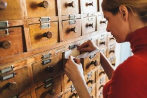 woman opening card catalog drawer