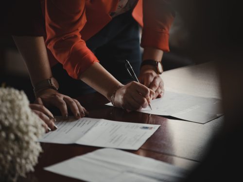 two people standing over desk signing paperwork