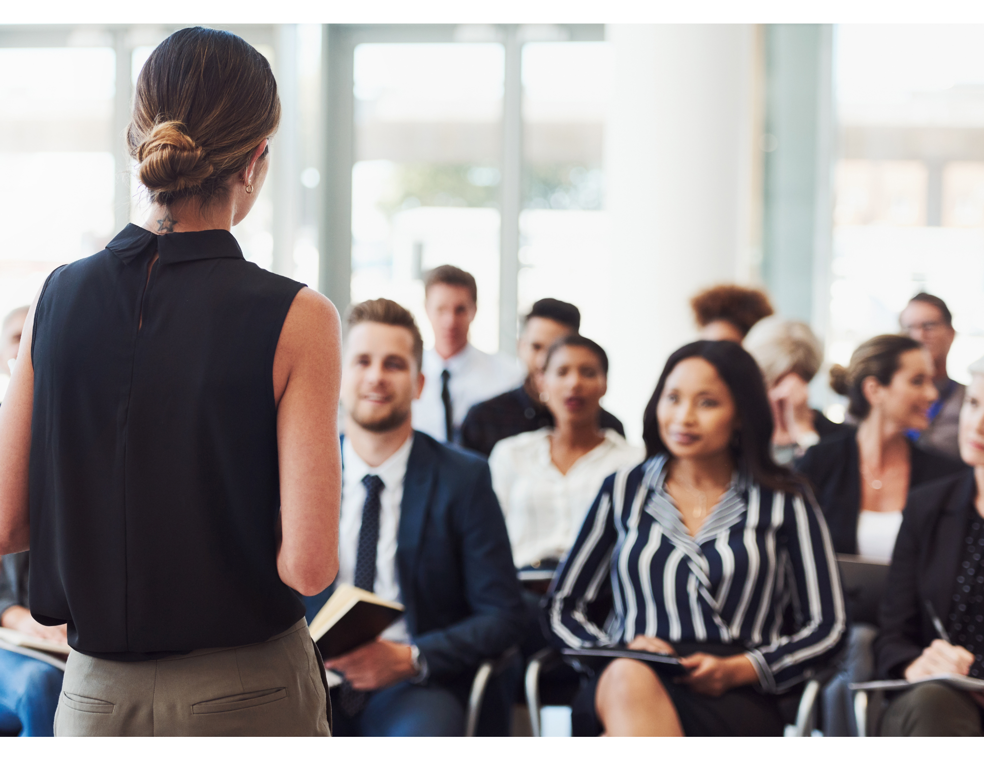 Woman stands in front of a seated audience and gives a presentation